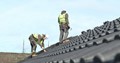 two construction workers on the roof of a house